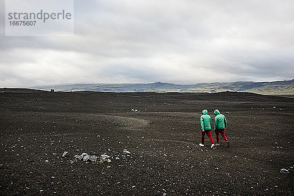 Wanderer erkunden einen schwarzen Sandstrand in der Nähe von Vik  Island.