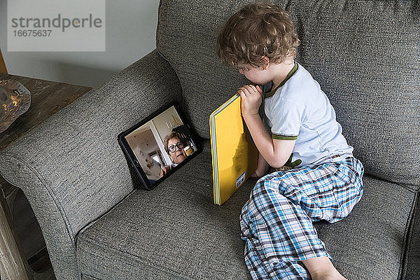 Vorschuljunge liest Buch mit Oma über Video-Chat