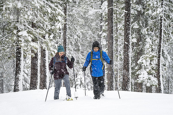 Schwarzer Mann und weiße Frau beim Skilanglauf im Wald