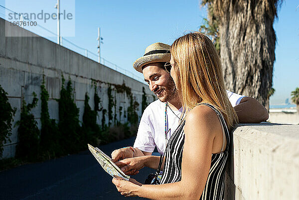 Glückliches Touristenpaar  das an einem sonnigen Tag im Freien einen Stadtplan überprüft