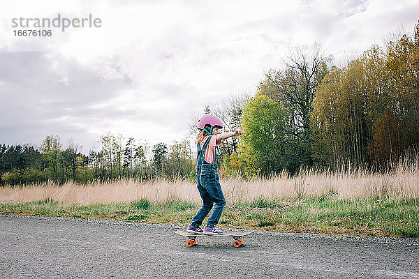 junges Mädchen lernt alleine Skateboard fahren