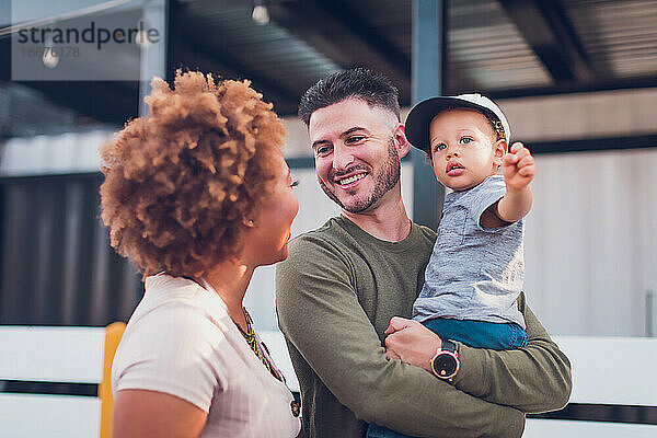 Der Vater hält den kleinen Jungen und sieht die Mutter an