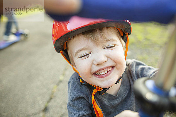 Lächelnder Junge mit rotem Helm beim Spielen draußen zu Hause