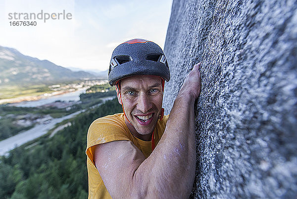 Mann kämpft beim Klettern im Vorstieg am Granit von Squamish mit der Weite