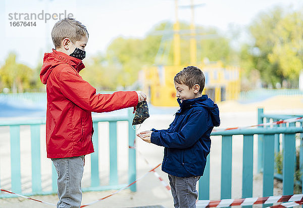 Kleiner Junge  der seinem Bruder eine Maske überreicht