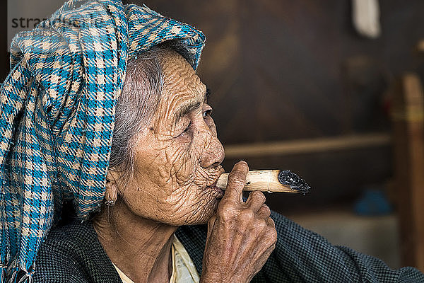 Seitenansicht einer nachdenklichen älteren birmanischen Frau beim Zigarrenrauchen  Bagan  Myanmar