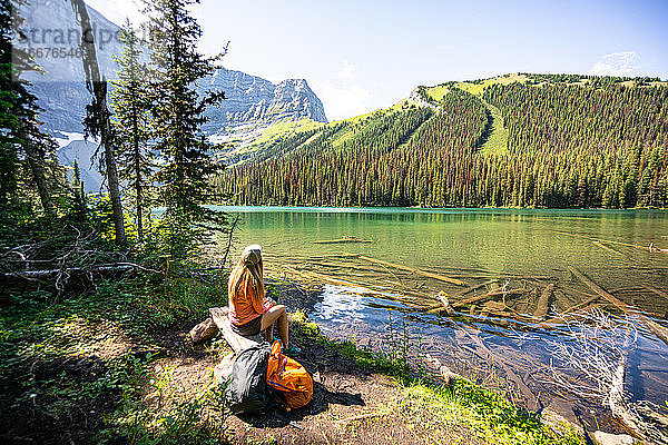 Wanderer sitzt am Rawson Lake und blickt in Richtung Sarrail Ridge in den Rockies