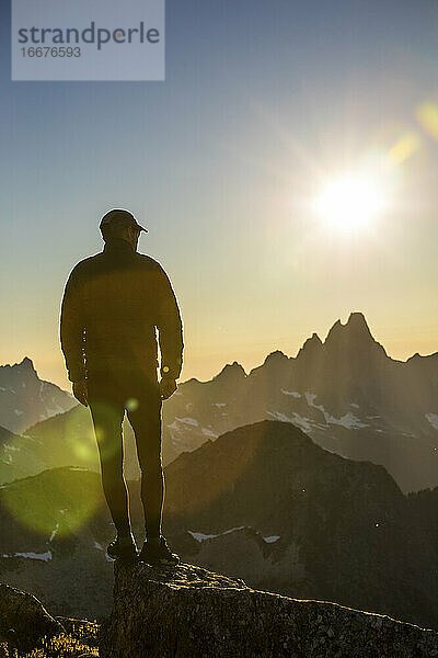 Silhouettierte Ansicht eines Wanderers auf einem Berggipfel  der eine malerische Gegend erkundet