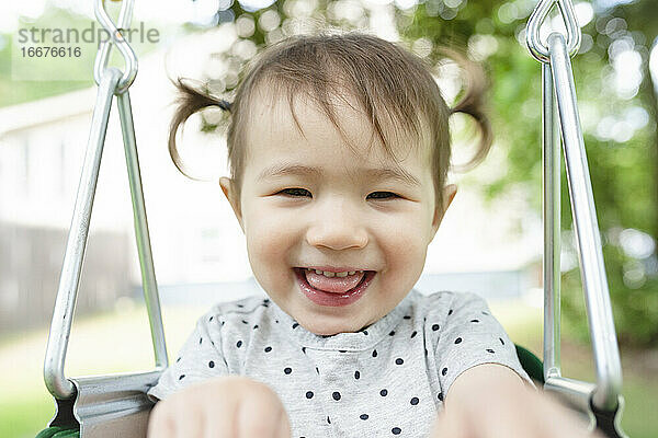 Nahaufnahme von Adorable Kleinkind Mädchen lächelnd in Backyard Swing
