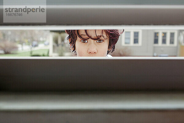 Ein neugieriges Kind  das draußen steht  späht in den Spalt eines offenen Fensters