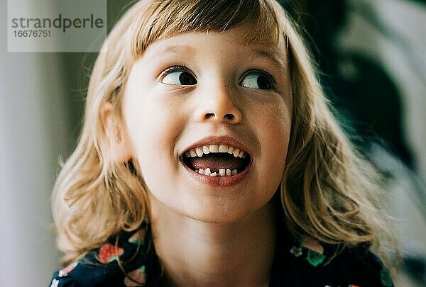 junges Mädchen  das lächelnd seinen wackeligen Zahn zeigt und glücklich aussieht