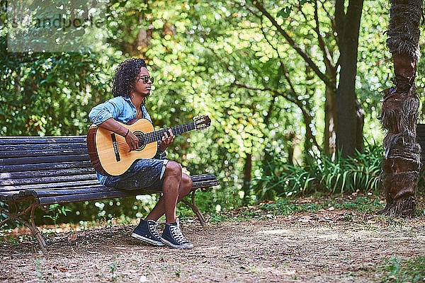Ein Musiker spielt Gitarre in einem schönen Park.