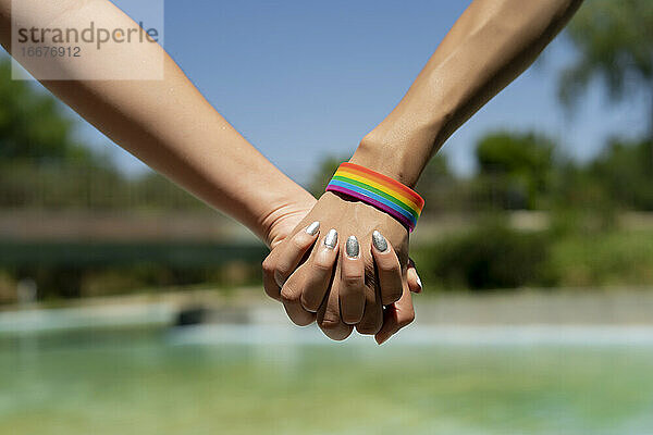 vereinte hände einer frau mit lgtbi armband