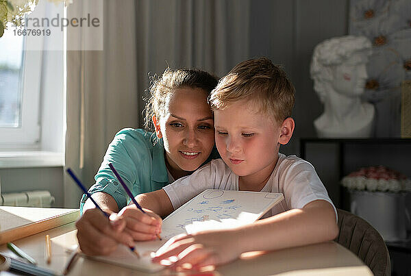 Konzentrierte Mutter und Sohn skizzieren im Planer