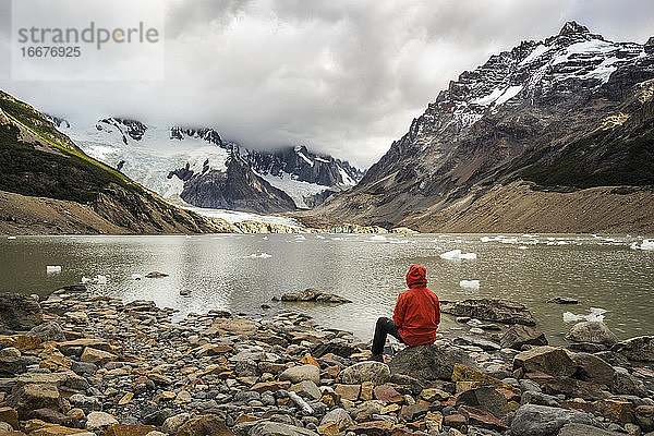 Rückansicht eines jungen Mannes in roter Jacke an der Laguna Torre  Los Glaciares National Park  El Chalten  Patagonien  Argentinien