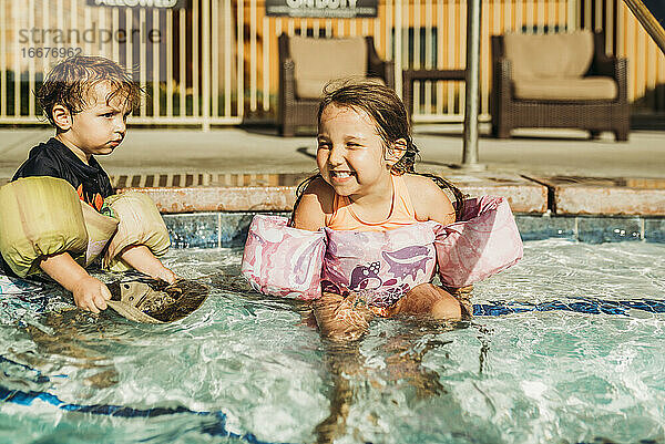 Vorderansicht von jungen Geschwistern  die im Urlaub in Kalifornien im Pool spielen