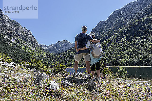 Touristisches Paar mittleren Alters  das sich in der Nähe eines Bergsees in den spanischen Pyrenäen umarmt See in den spanischen Pyrenäen