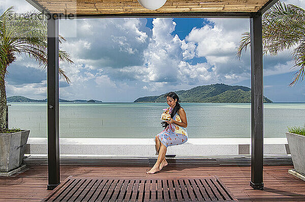 schöne Frau genießt Kokosnusssaft auf dem Dach eines Luxusresorts