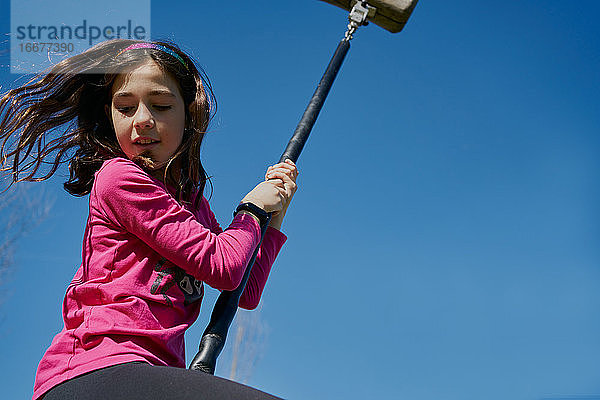 Mädchen auf einer Kinder-Seilrutsche mit blauem Himmel im Hintergrund