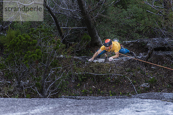 Mann klettert im Wald am oberen Seil Squamish Chief