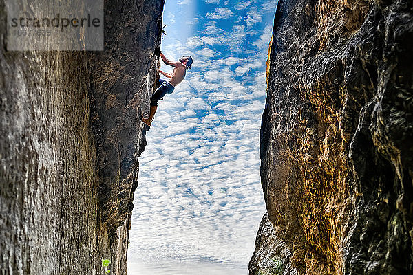 Junger Mann klettert seilfrei an einer vertikalen Wand