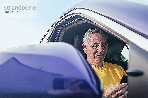 Positiver älterer männlicher Reisender verklagt Smartphone im Auto