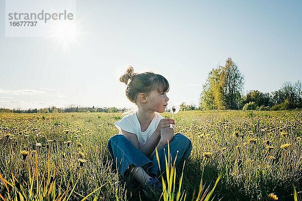 Ein junges Mädchen saß in einem friedlichen Blumenfeld im Sommer
