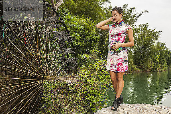 schöne Frau steht neben einer Wassermühle in Yangshuo