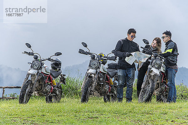 Drei Freunde schauen auf einer Motorradtour auf die Karte