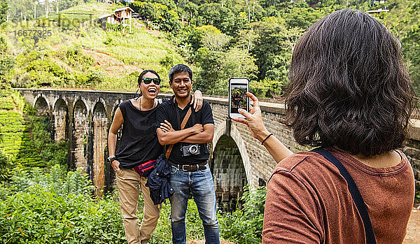 Frau  die ein Foto von ihren Freunden an der berühmten Nine Arch Bridge macht