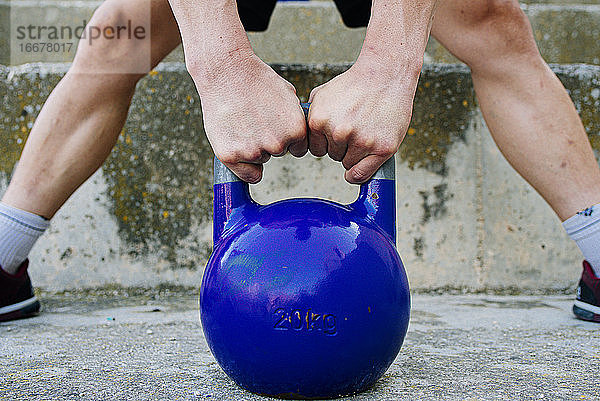 Mann hebt ein Kettelbell-Crossfit-Gewicht in einer städtischen Umgebung.