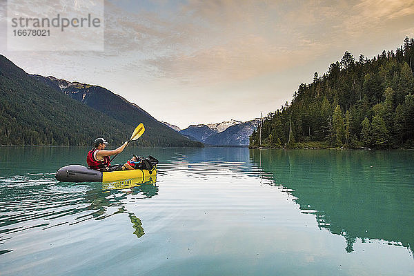 Vater paddelt mit seinem Sohn in einem Schlauchboot auf einem See.