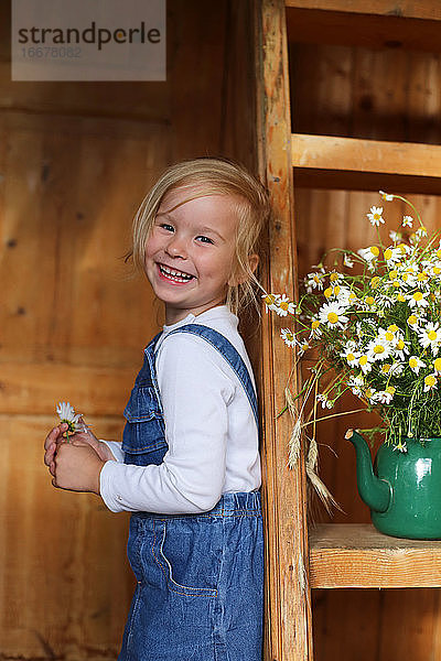 Bild eines glücklichen Mädchens neben einem Strauß Gänseblümchen.