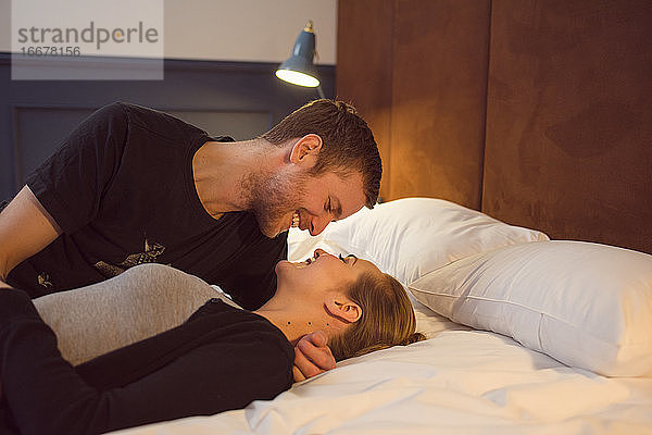 Optimistisches Paar kuschelnd auf dem Bett