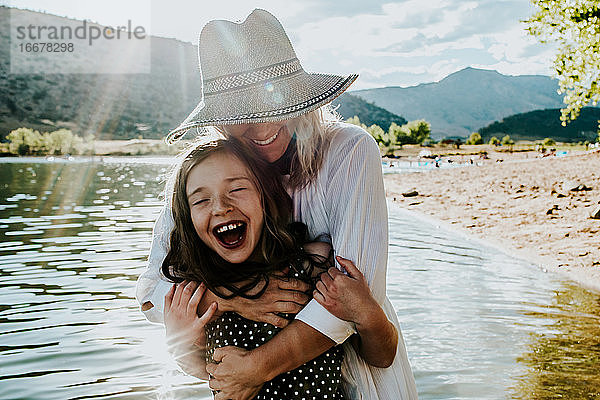 Mutter und Tochter umarmen sich und lachen  während sie in einem See stehen