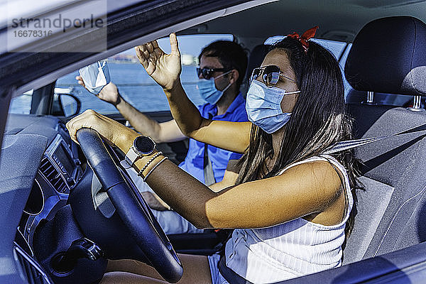 Paar mit Gesichtsmaske streitet  während sie in einem gefährlichen Auto fährt
