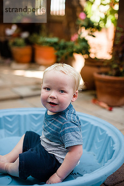 Ein Jahr alter Junge im Pool sitzend im Garten in San Diego