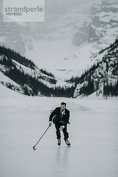 Mann im Anzug spielt Eishockey auf dem zugefrorenen Lake Louise  Alberta  Kanada