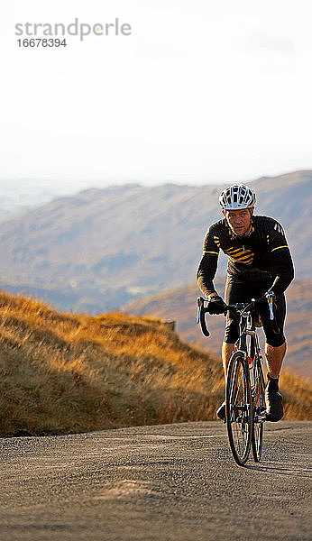 Radfahrer  der sich dem Gipfel eines Hügels im britischen Lake District nähert