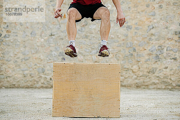 Ein Mann übt Crossfit und springt in eine plyometrische Box.