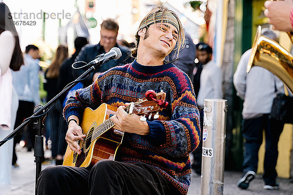 Junger Mann spielt Gitarre auf der Straße