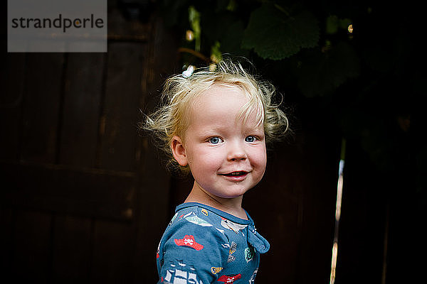 Blondes zweijähriges Kind im Schlafanzug lächelt für die Kamera