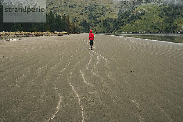 Junge Frau mit roter Jacke am Strand von Okains Bay  Banks Peninsula