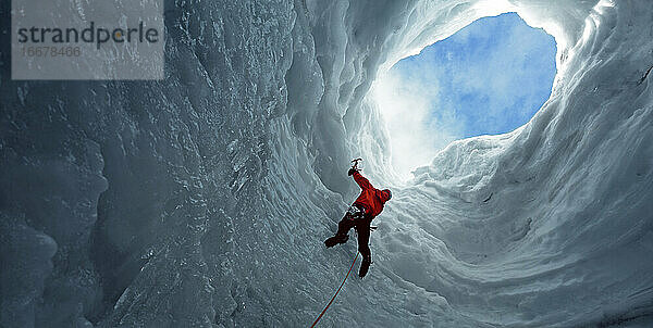 Mann klettert zu einer Öffnung in einer Eishöhle am Langjokull-Gletscher