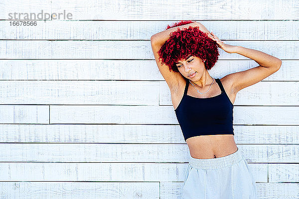 Porträt einer Frau mit rotem Afro-Haar  die vor einem weißen Hintergrund posiert.