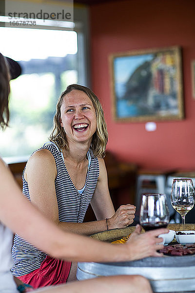 Eine junge Frau lacht  während sie in einem Weingut in The Dalles  OR  Wein genießt.