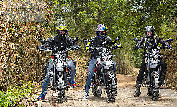 Drei Freunde fahren mit ihren Scrambler-Motorrädern durch den Wald