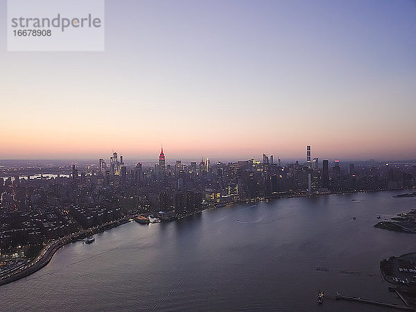 Wide Aerial Drone Ansicht von Manhattan Skyline mit East River in New York City in der Abenddämmerung und Lichter der Stadt