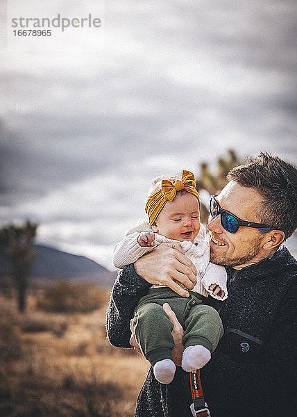 Ein Mann mit einem Baby steht in der Wüste von Kalifornien