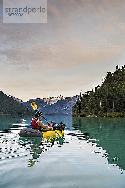 Vater paddelt mit seinem Sohn auf einem malerischen See in Kanada.